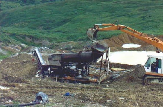 Alluvial gold trommel screen being fed by an excavator